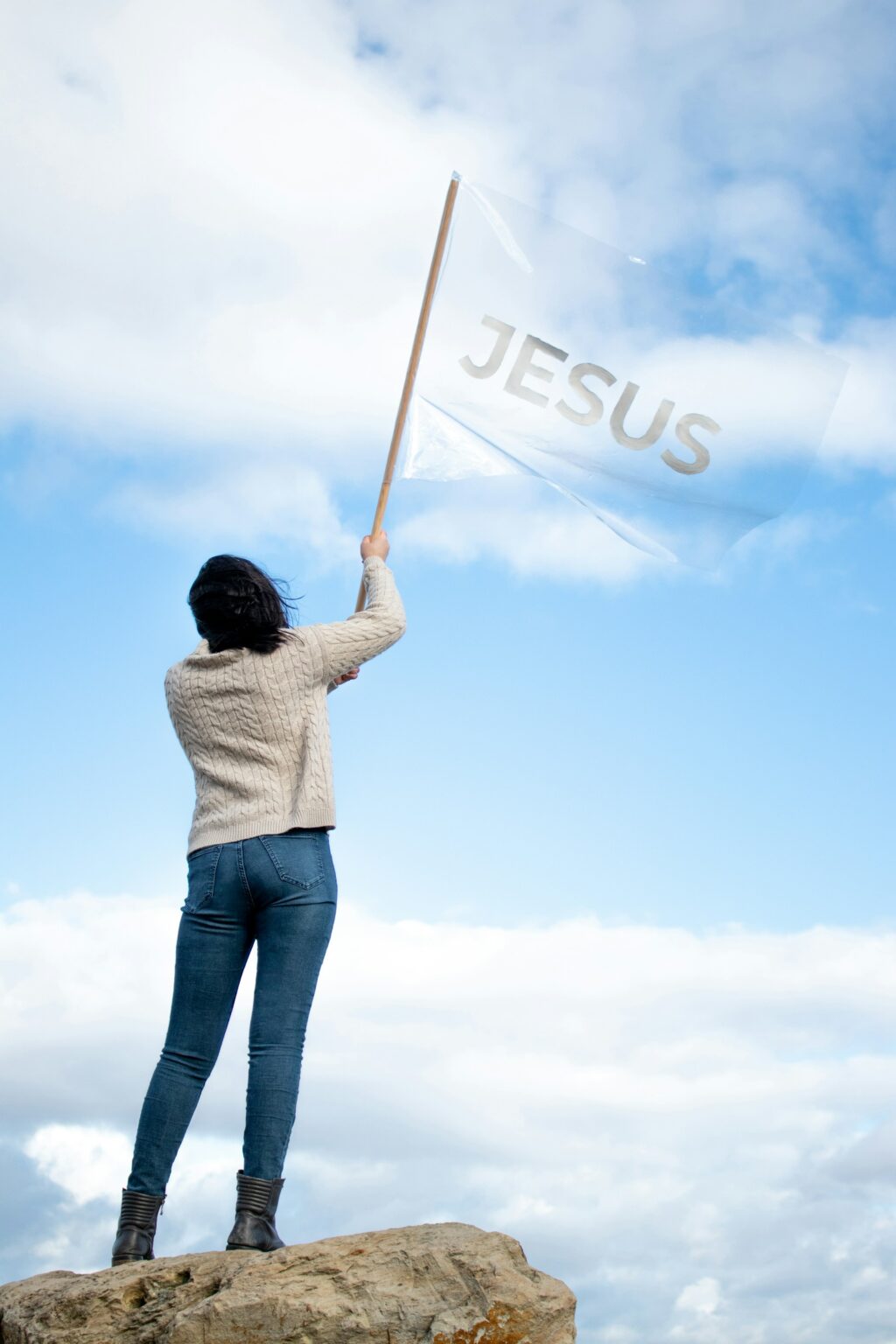 woman in white shirt blue denim jeans holding jesus flag