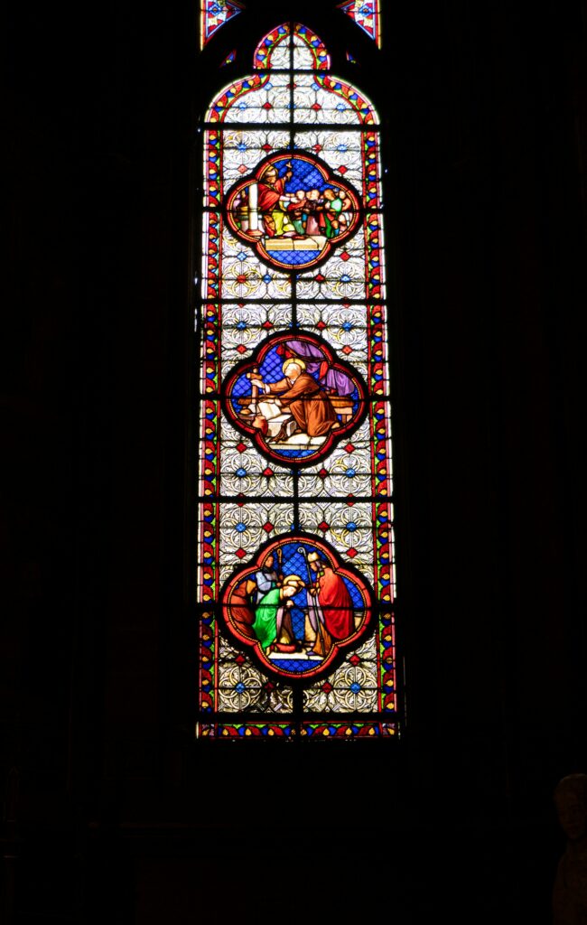 a stained glass window in a dark background eliott goutard from unsplash