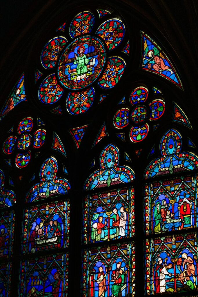 colorful stained glass window inside a church jimmy woo from unsplash