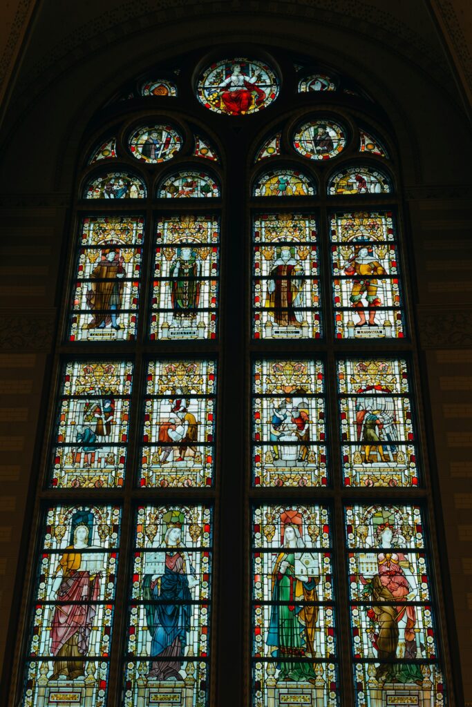 a large stained glass window in a church fuji nakama from unsplash