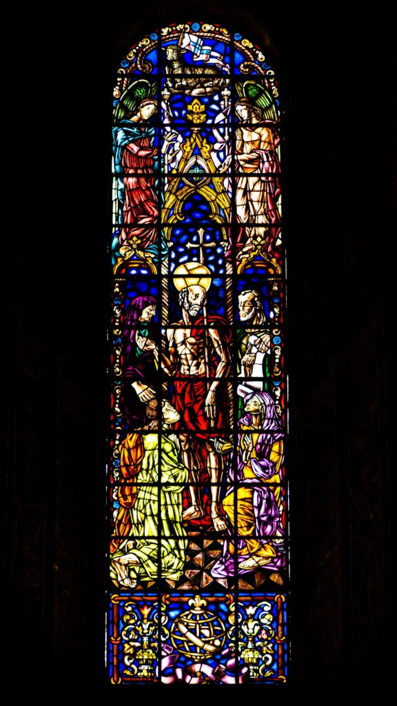 a large stained glass window in a dark background aalvin david from unsplash