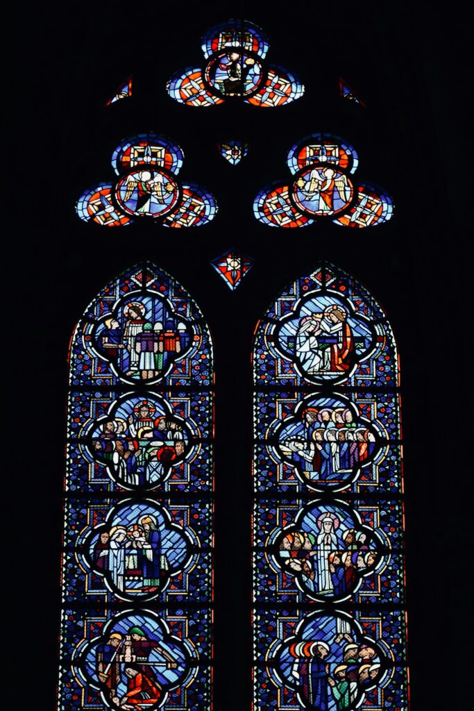 a stained glass window with chartres cathedral in the background sarah nikiforoff from unsplash